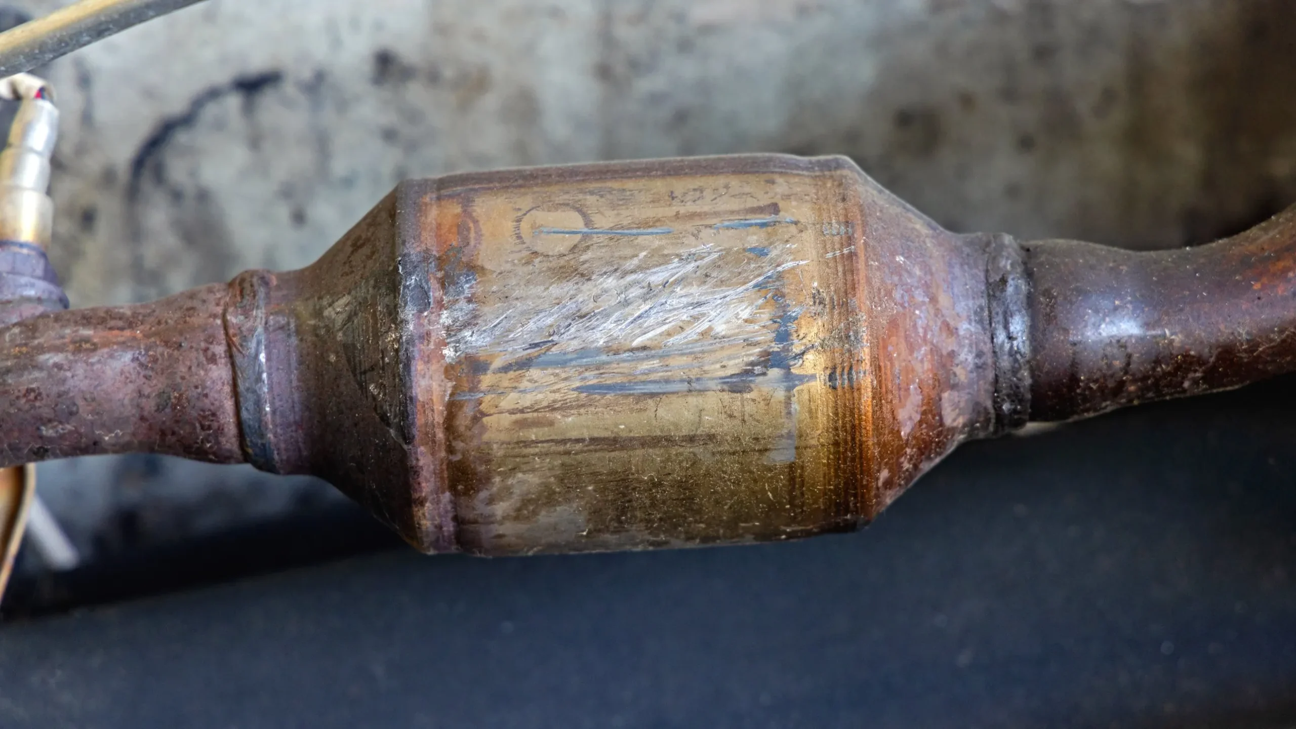 Close-up of a rusty catalytic converter on an exhaust pipe